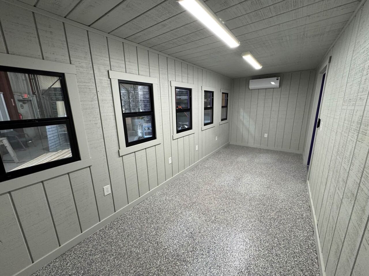 Dense charcoal, gray and white flake epoxy floor in a modular office by SurfaceKings